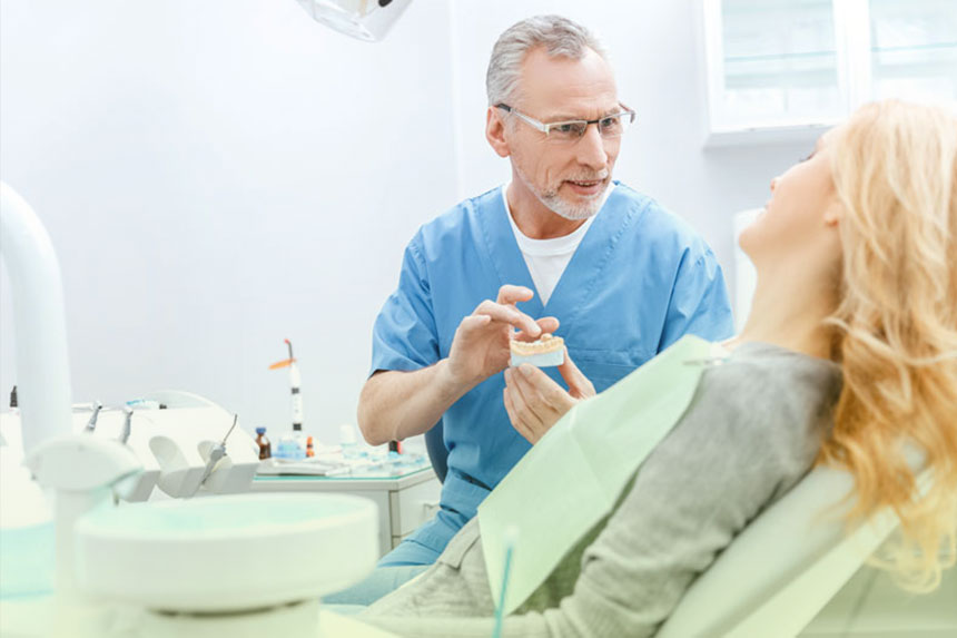 Dentist showing a dental model to a patient while explaining treatment options at Dr. Brent MacDonald’s Calgary clinic.