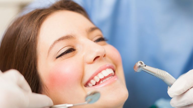 Close-up of female patient undergoing professional teeth cleaning with dental instruments during a check-up.