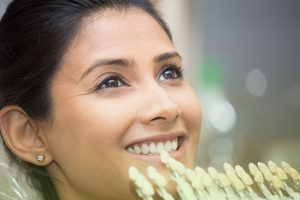 Close-up of a Calgary dentist matching a veneer shade tray to a woman’s teeth during a cosmetic dentistry consultation