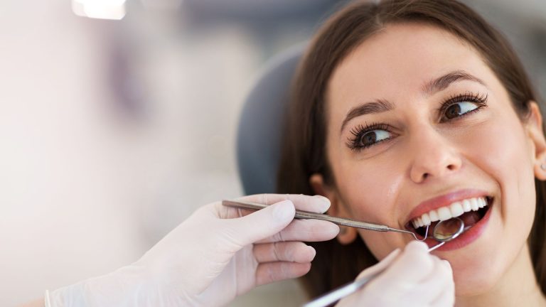 Woman receiving a dental check-up with mirror and probe during a cavity examination before a filling procedure.