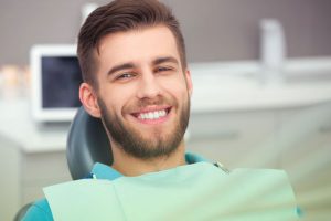 A young man smiling confidently after a successful tooth crown procedure at Dr. Brent MacDonald’s dental clinic in NE Calgary.