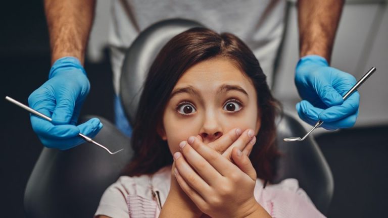 A Fearful Small Girl Covering Her Mouth For Dental Treatment