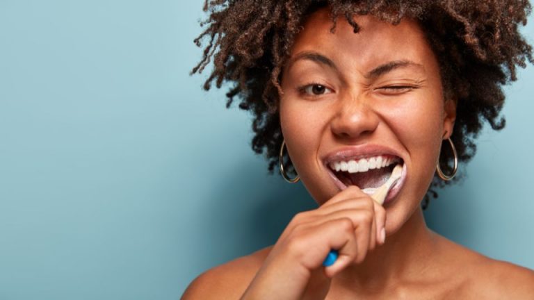 Woman brushing her teeth after a professional whitening treatment to maintain a bright and healthy smile