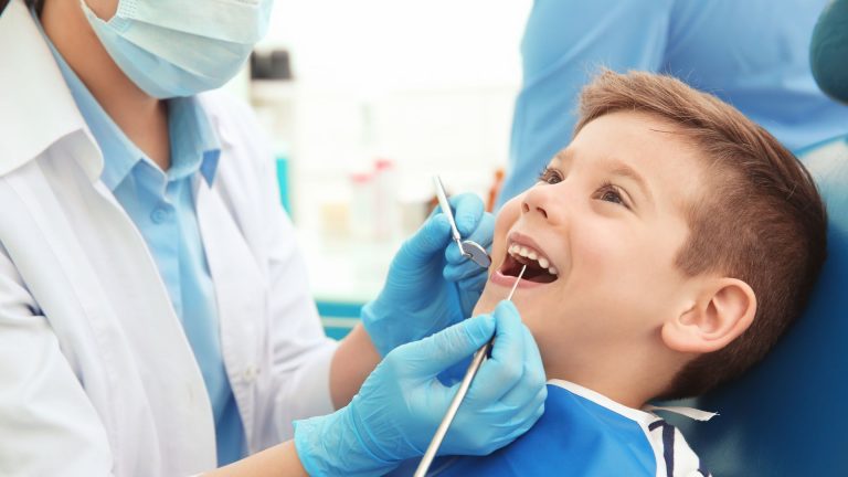 Smiling young boy having a dental check-up with a dentist at Dr. Brent MacDonald’s Calgary clinic for children’s dentistry.