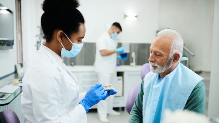 A dentist explaining different denture options to a patient during a consultation in a dental clinic in NE, Calgary