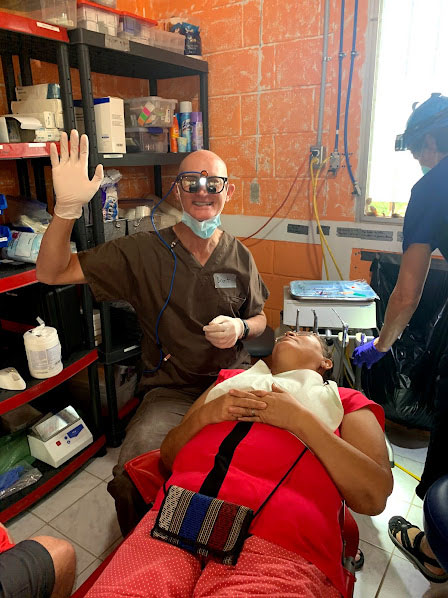 Dr. MacDonald volunteering on a dental mission, providing care to a patient in a community clinic.
