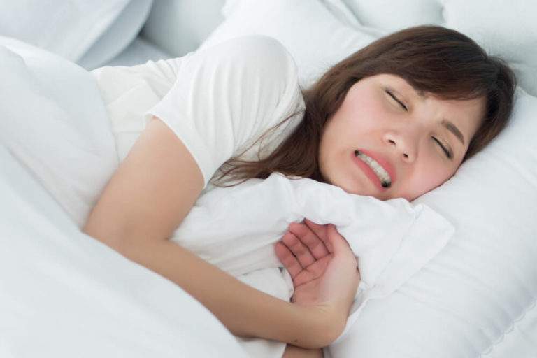 Young girl experiencing teeth clenching and bruxism while sleeping, a condition treated at Dr. Brent MacDonald’s Calgary dental clinic.